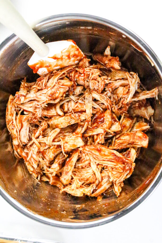 A picture of shredded chicken and barbecue sauce mixed together in a bowl.