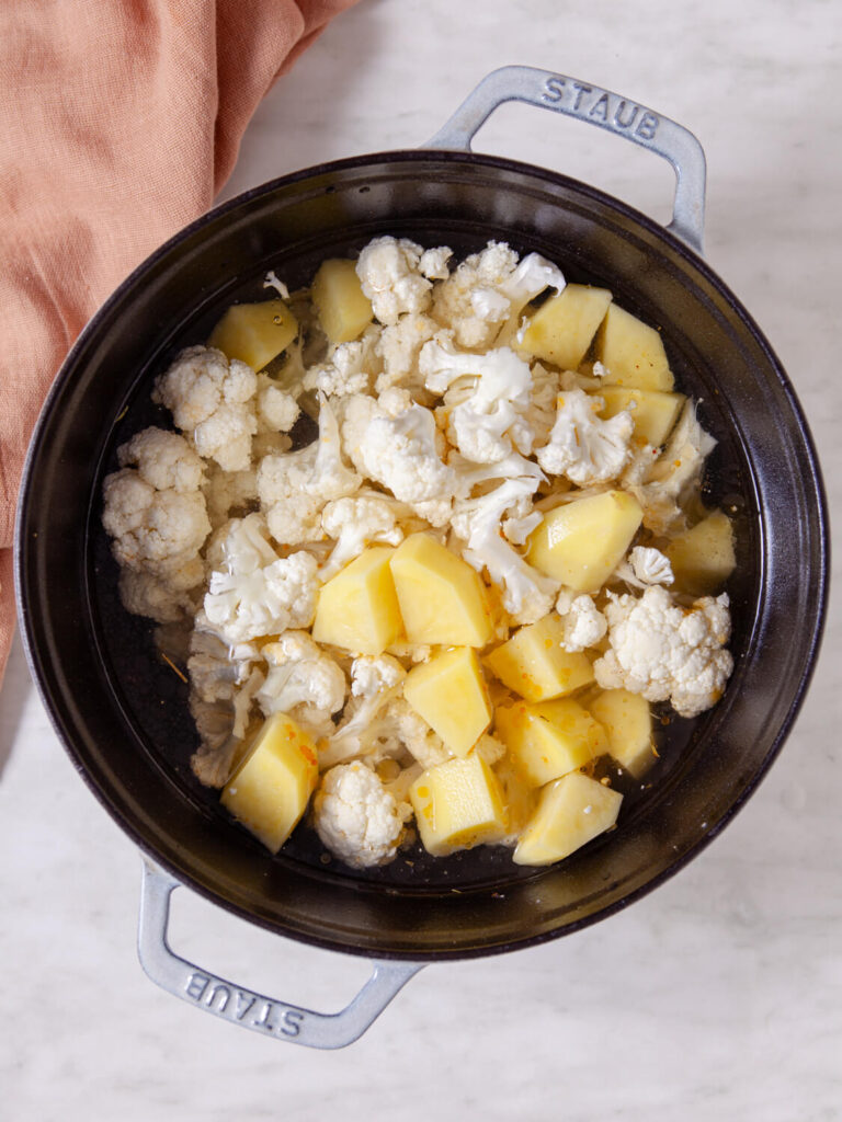 A picture ofcauliflower and potatoes cooking in a pot.