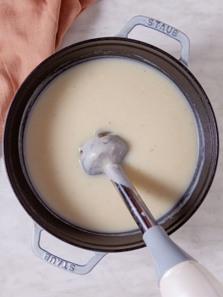 A picture of soup being pureed in a pot with an immersion blender.