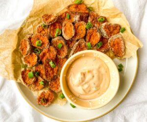 A picture of a platter of pickle chips with dipping sauce.