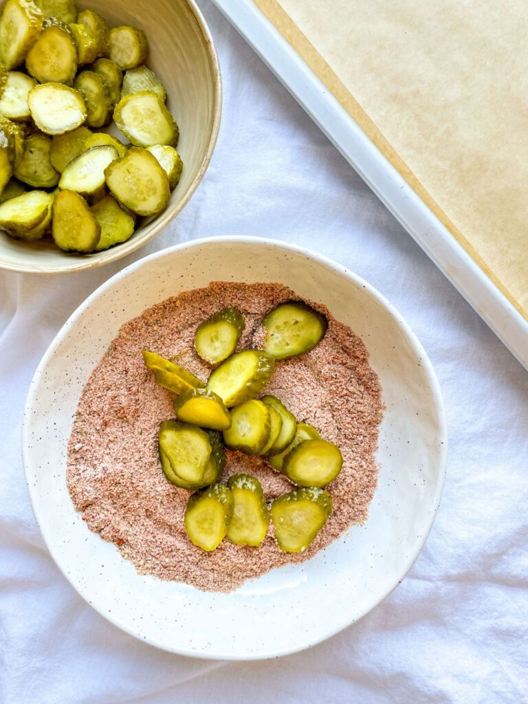 A picture of sliced pickles in a bowl with a breadcrumb mixture.