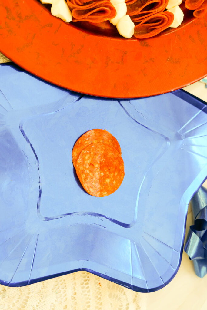 A picture of two pieces of pepperoni overlapping each other on a star shaped plate.