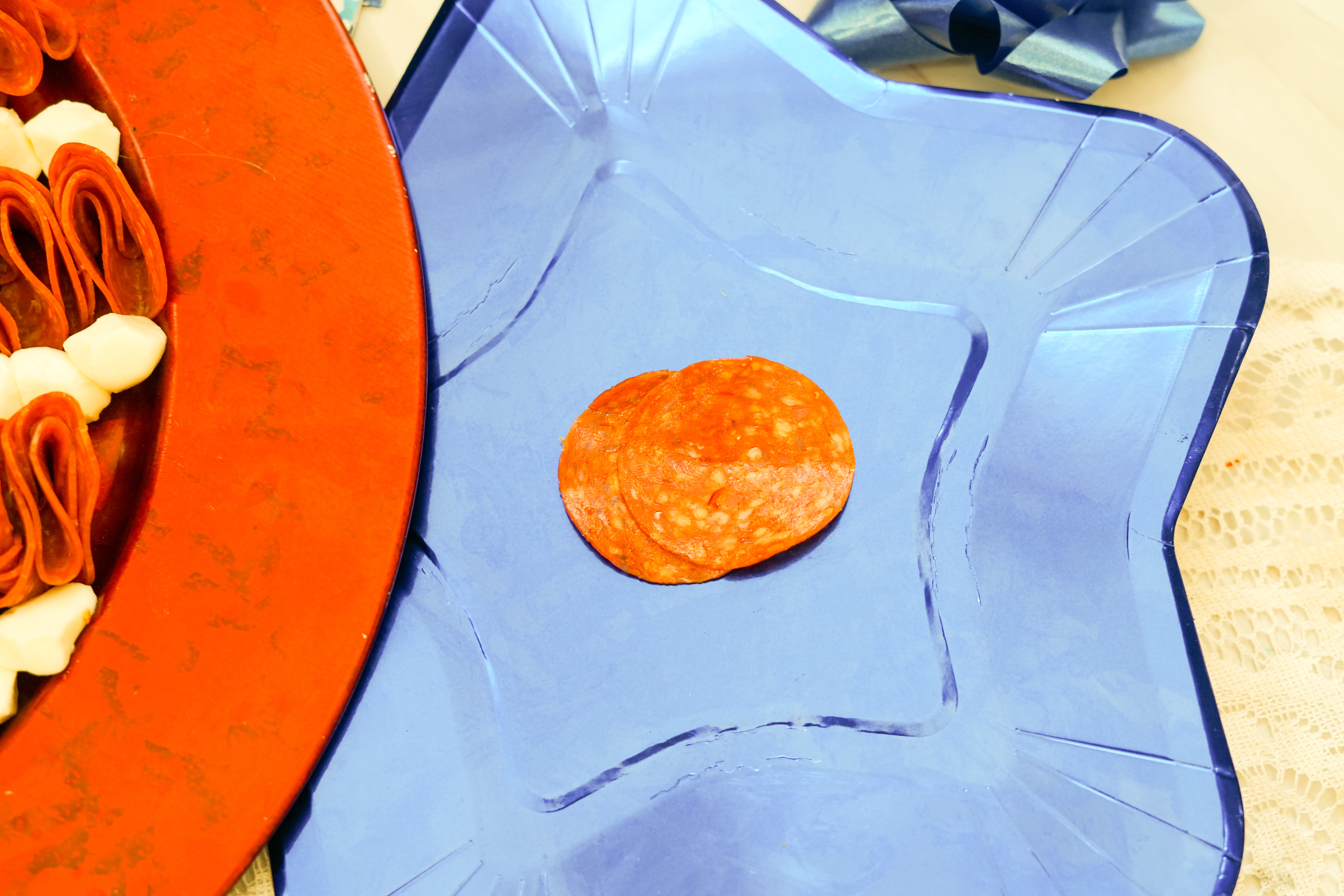 A picture of two pieces of pepperoni overlapping each other on a plate.