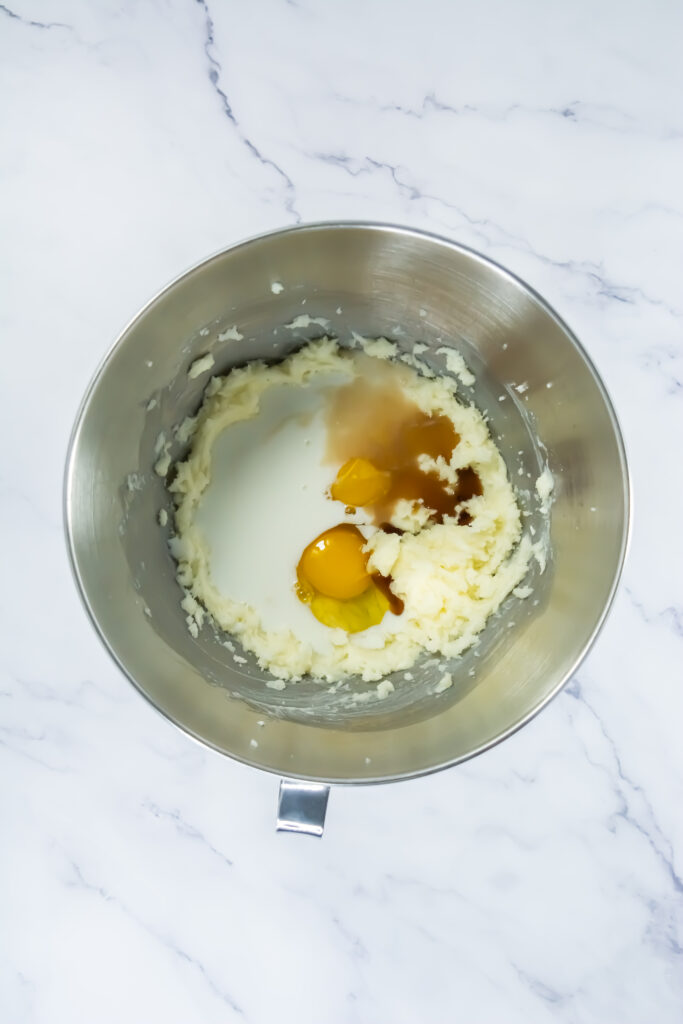 A picture of milk, vanilla, and eggs unmixed in a bowl with a butter and sugar.