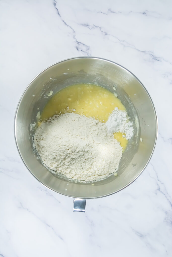 A picture of flour, baking powder, and salt in a bowl with a whisked butter mixture.