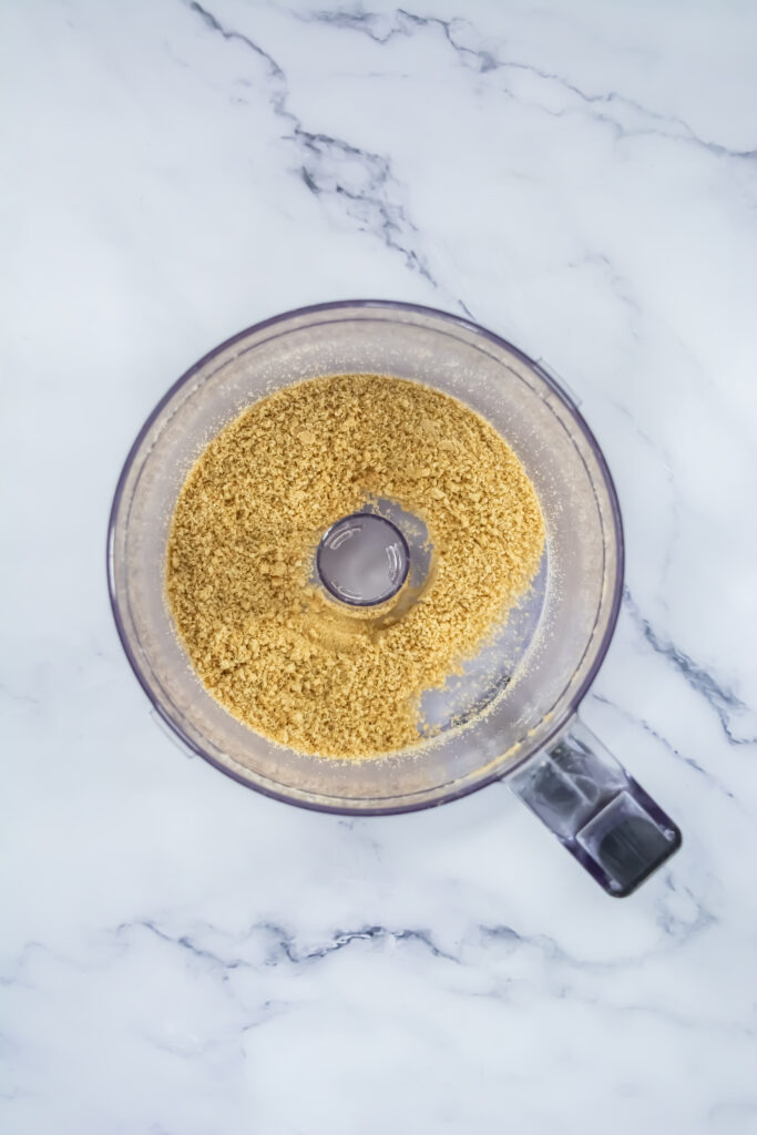 A picture of Teddy Graham cookies ground into crumbs in a food processor.