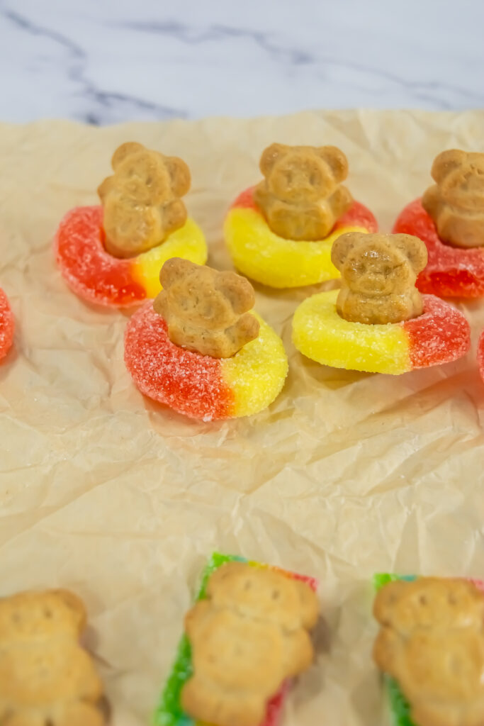A picture of Teddy Graham cookies placed into peach ring candies to resemble inner tubes.