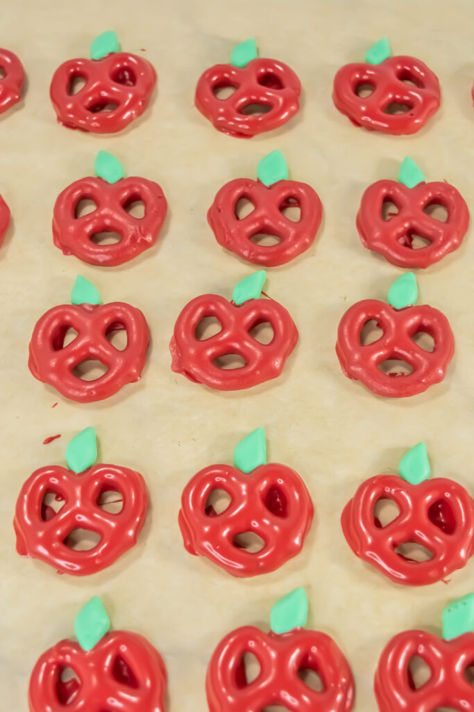 A close up picture of candy coated pretzels cooling on a baking sheet.