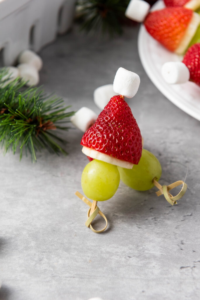 A zoomed in picture of two Christmas themed fruit skewers stacked on top of one another.