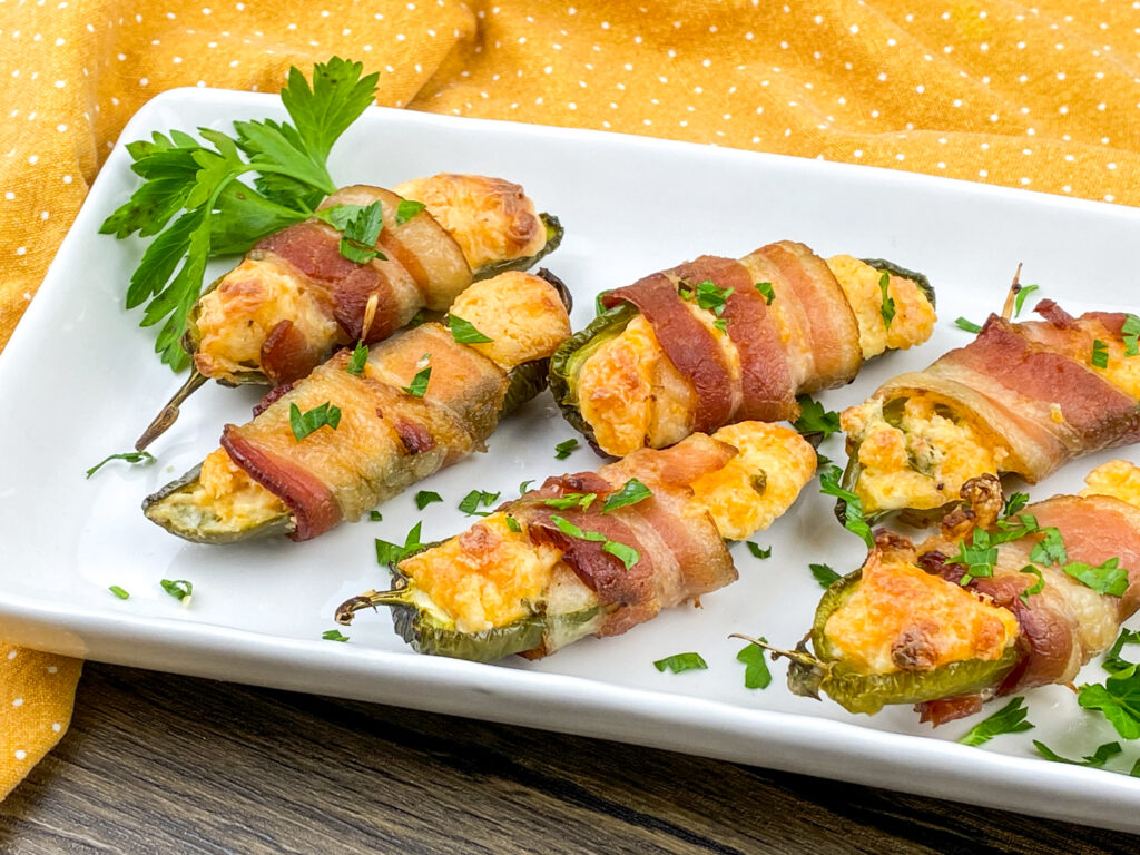 Jalapeno poppers laid out in two rows on a plate.