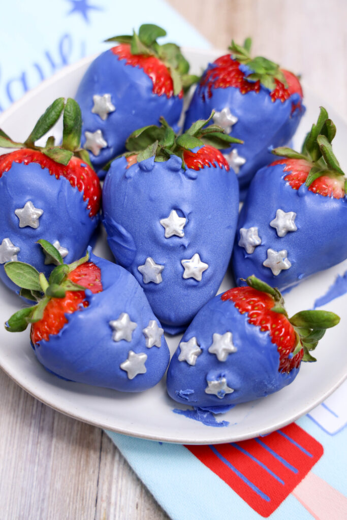 A picture of a set of candy coated strawberries on a plate in three rows.