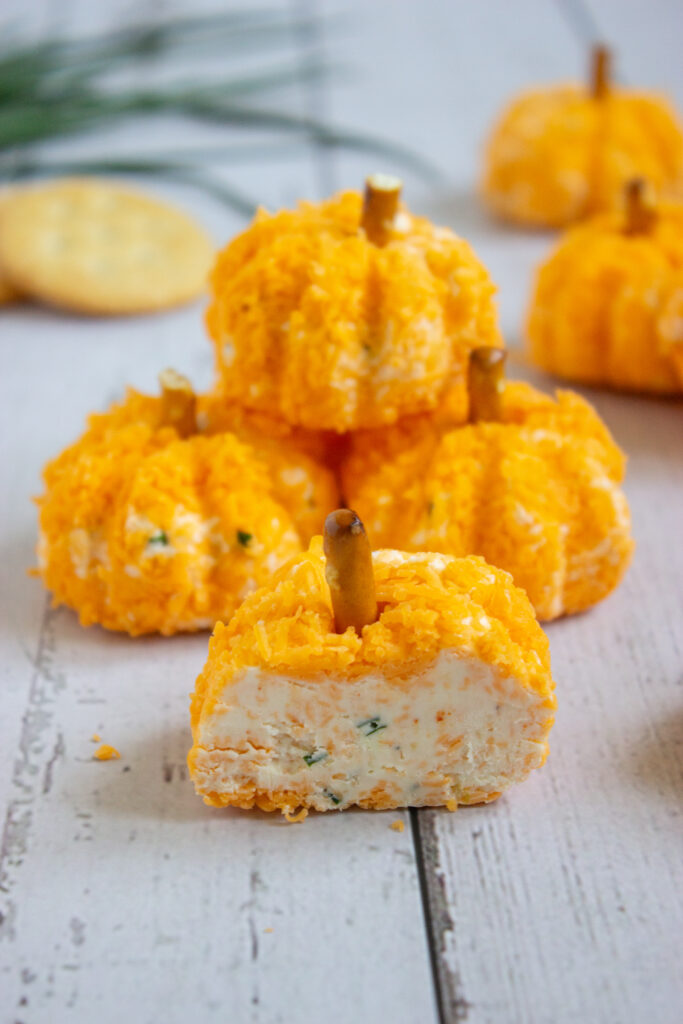 A picture of a set of pumpkin cheeseballs with a bite taken out of one in the foreground.