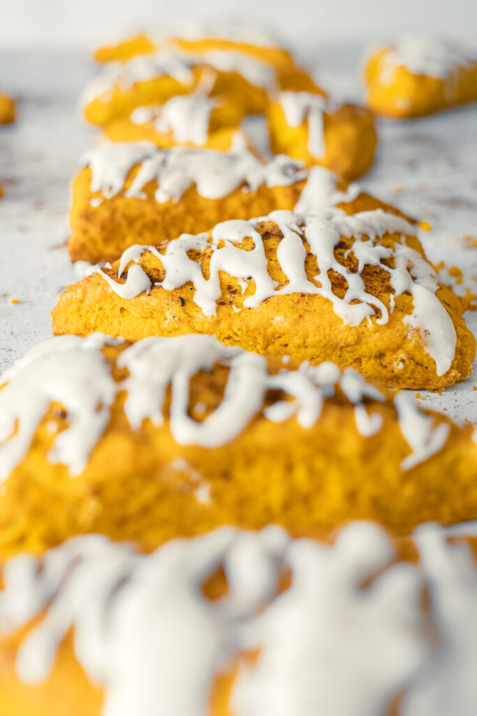 A picture of a row of glazed pumpkin spice scones.