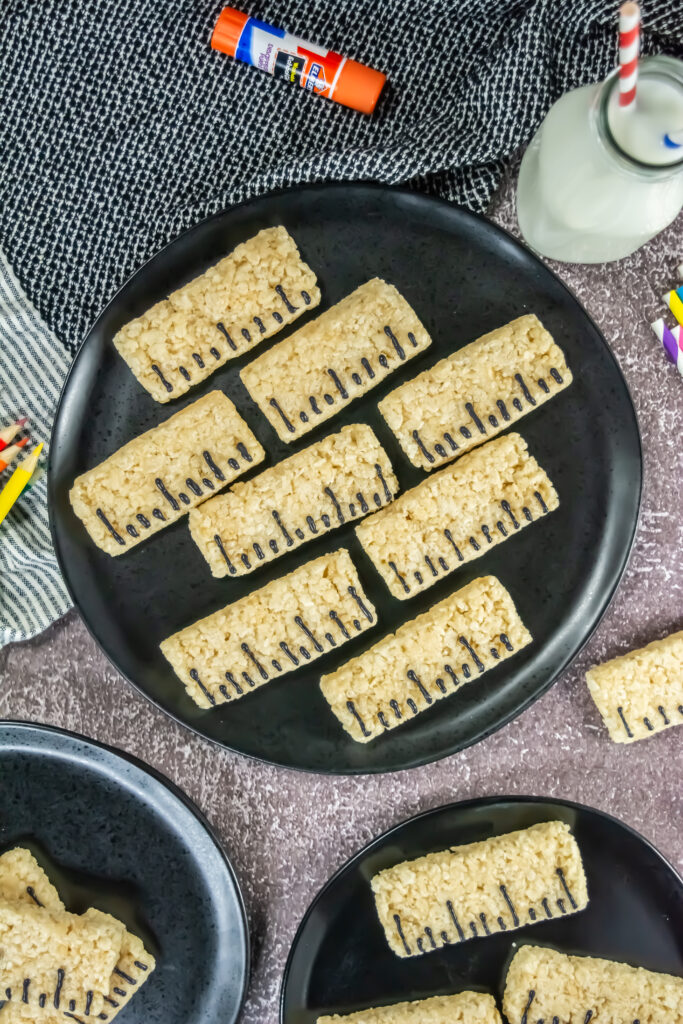 An overhead picture of ruler rice krispy treats near a glass of milk.