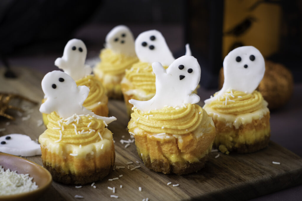 A picture of round mini cheesecakes topped with candy ghosts.