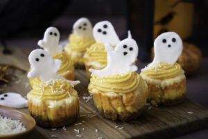 A picture of round mini cheesecakes topped with candy ghosts.
