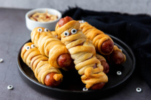 A picture of a plate of hot dogs wrapped and fried in crescent roll dough.