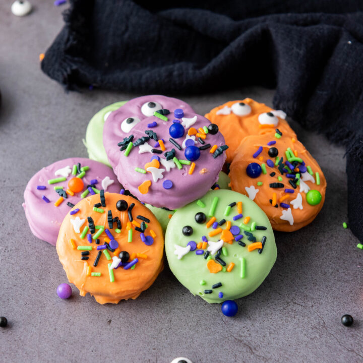 A picture of a small pile of candy dipped oreo cookies.