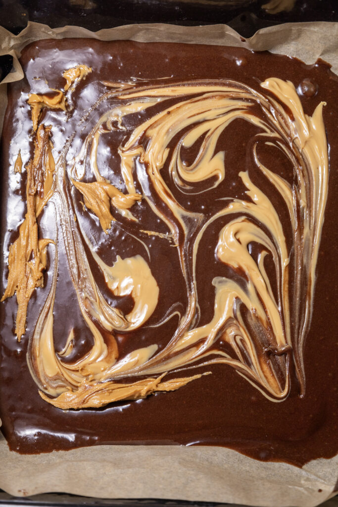 A picture of peanut butter swirled into brownie mix in a baking pan.
