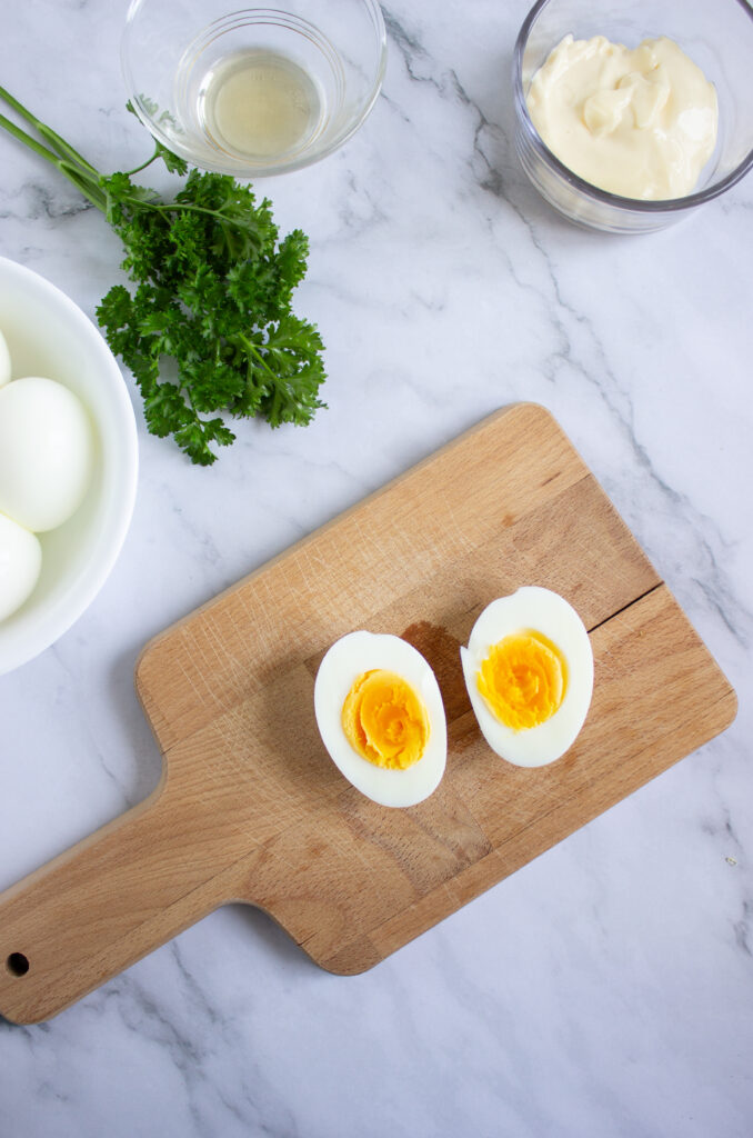 A picture of a hard boiled egg sliced in half on a wooden cutting board.