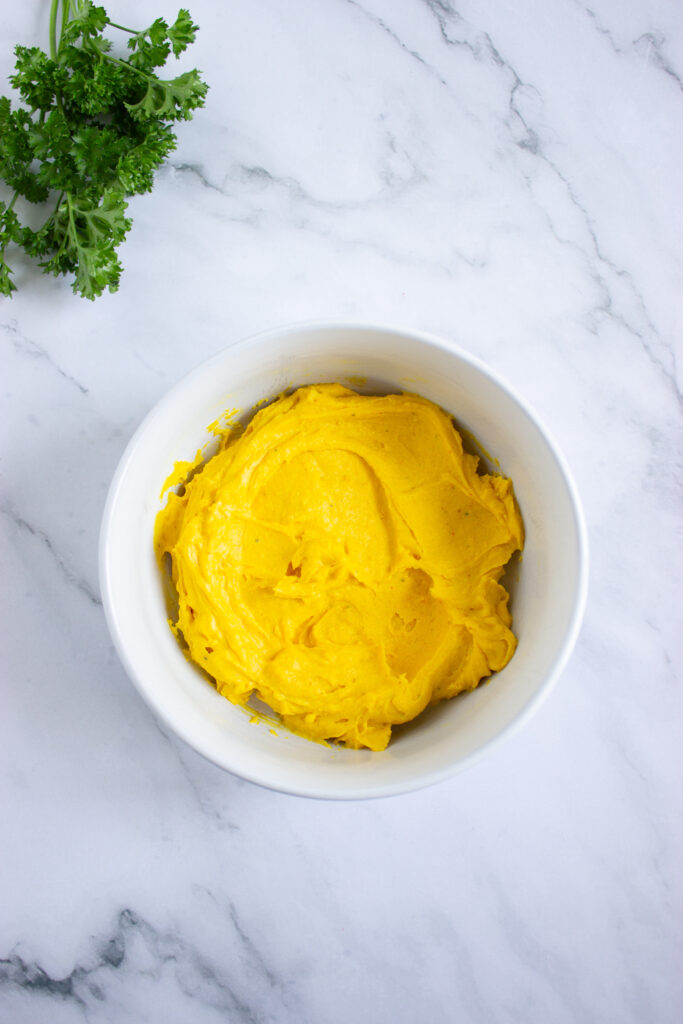 A picture of hard boiled egg yolks, mayonnaise, dijon mustard, spices, and vinegar mixed together to make a paste.