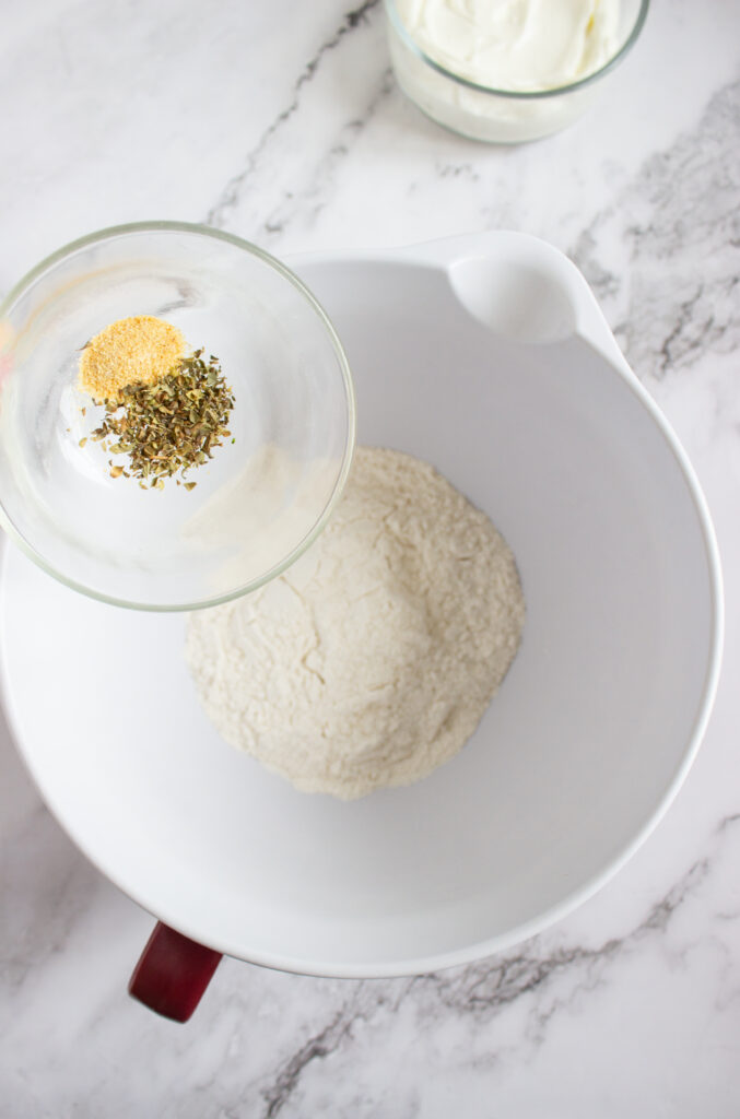 A picture of spices being aded to a bowl of flour.