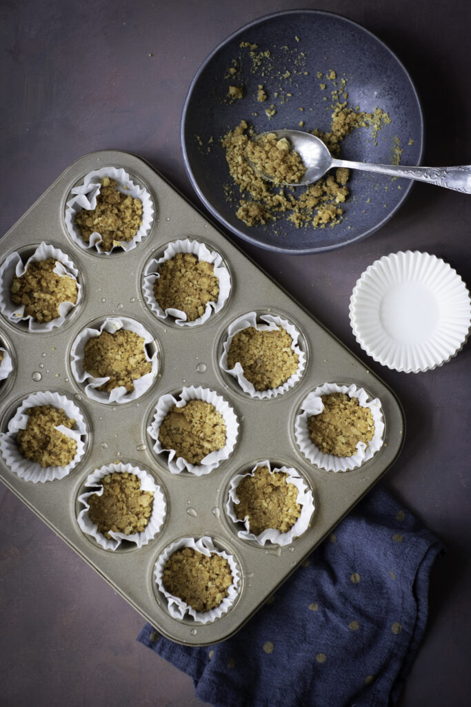 A picture of unbaked graham cracker crust in cupcake tins.