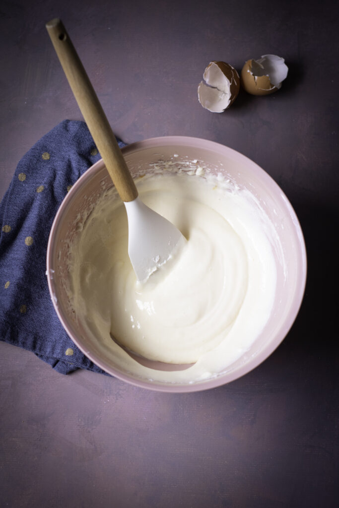 A picture of softened cream cheese, granulated sugar, and eggs mixed together in a bowl.