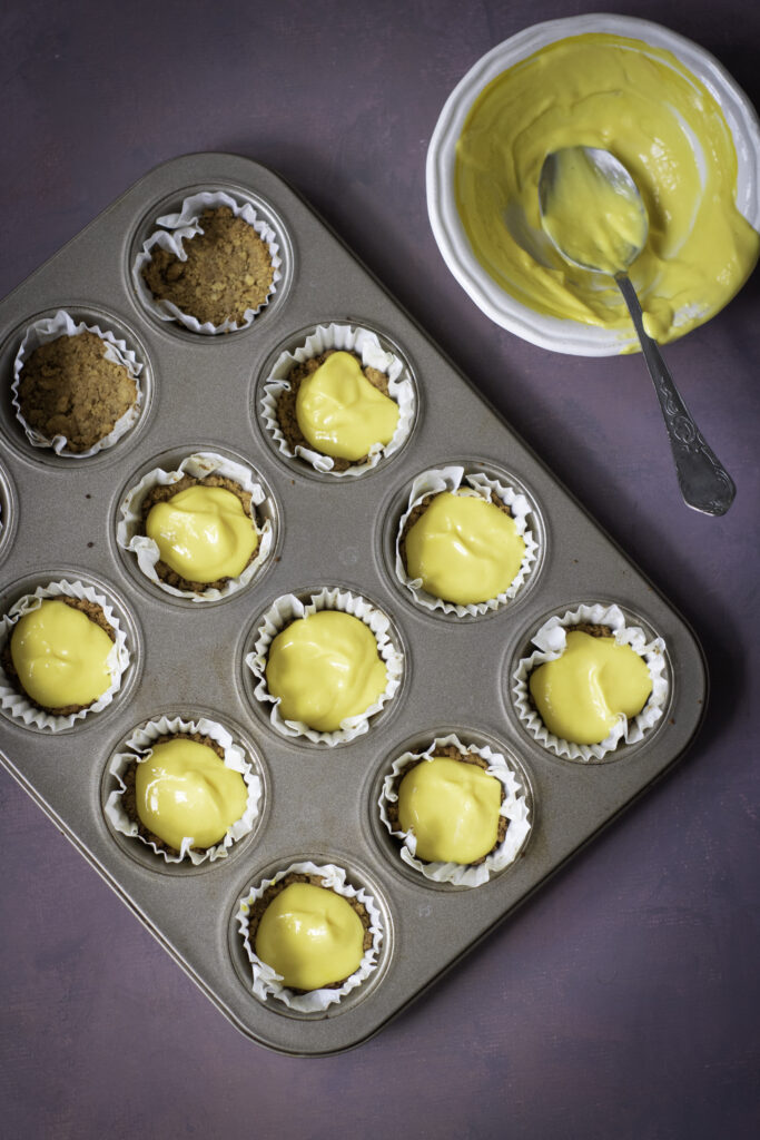 A picture of yellow cheesecake batter in cupcake tins.