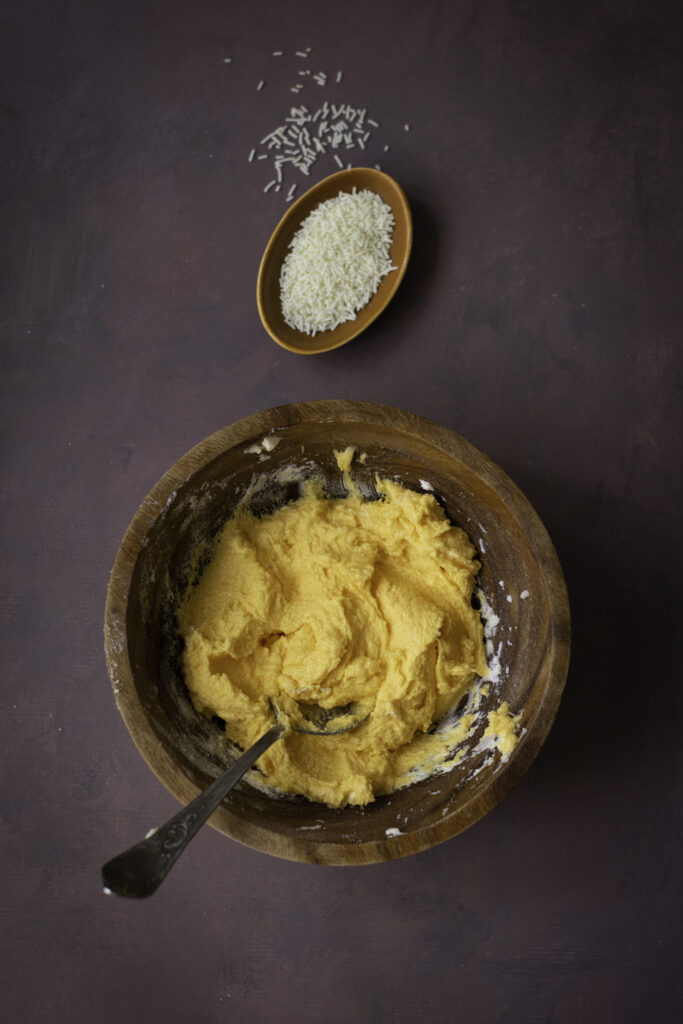 A picture of butter, powdered sugar, cream, and vanilla extract mixed up together in a bowl.
