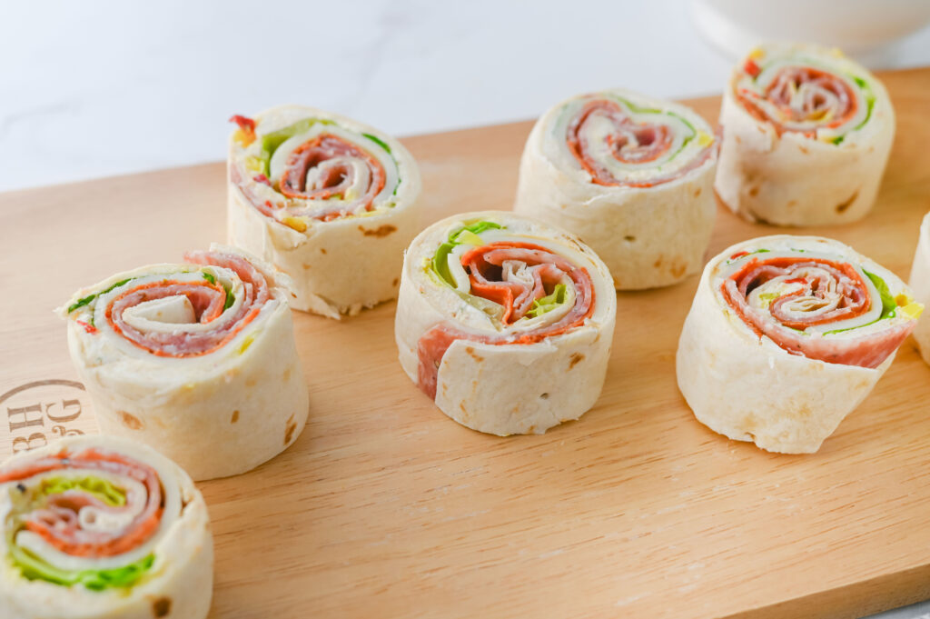 A picture of sliced italian pinwheel sandwiches on a cutting board.