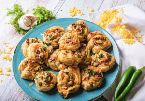 A picture of a set of jalapeño popper pinwheel sandwiches stacked on a plate.