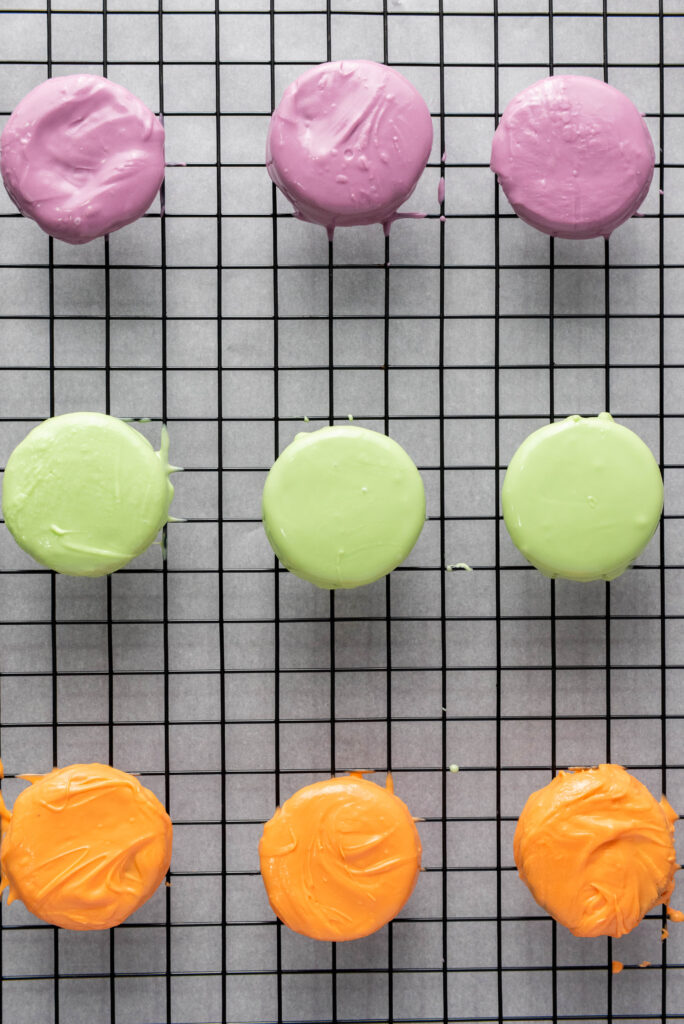 A picture of three rows of oreos dipped in purple, green, and orange melted candy.