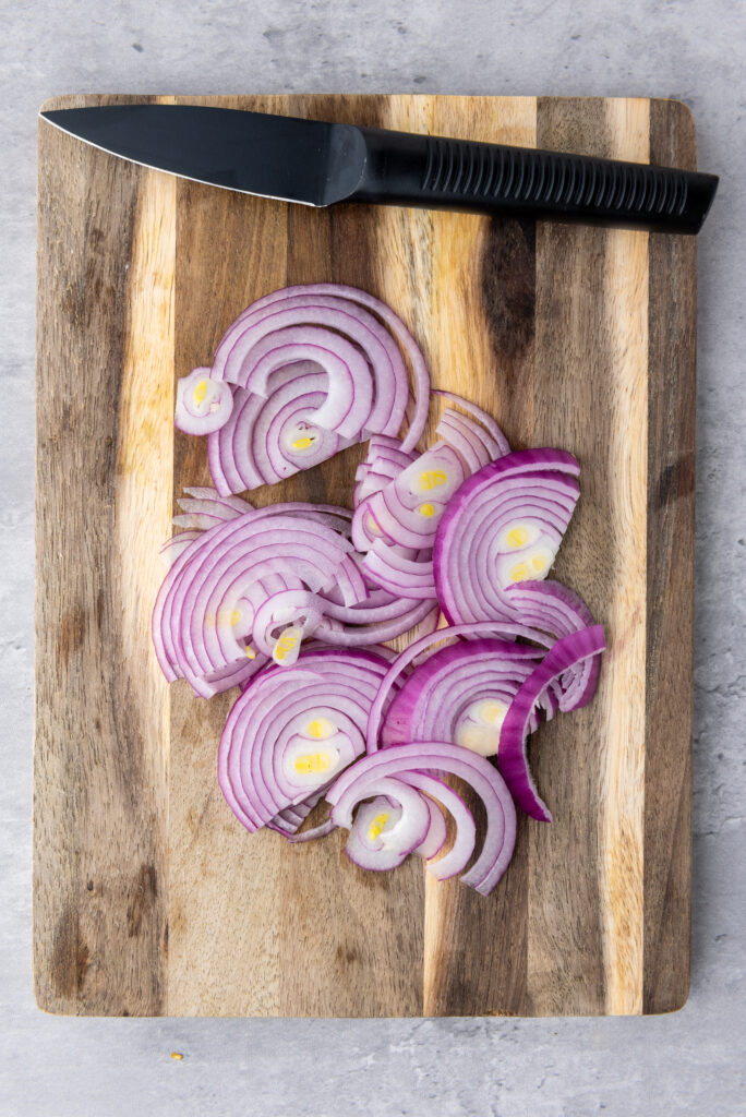 A picture of sliced red onions on a cutting board.