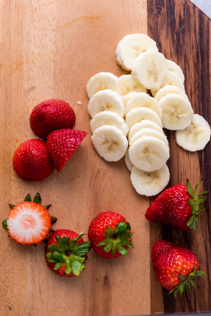 A picture of sliced bananas and hulled strawberries.