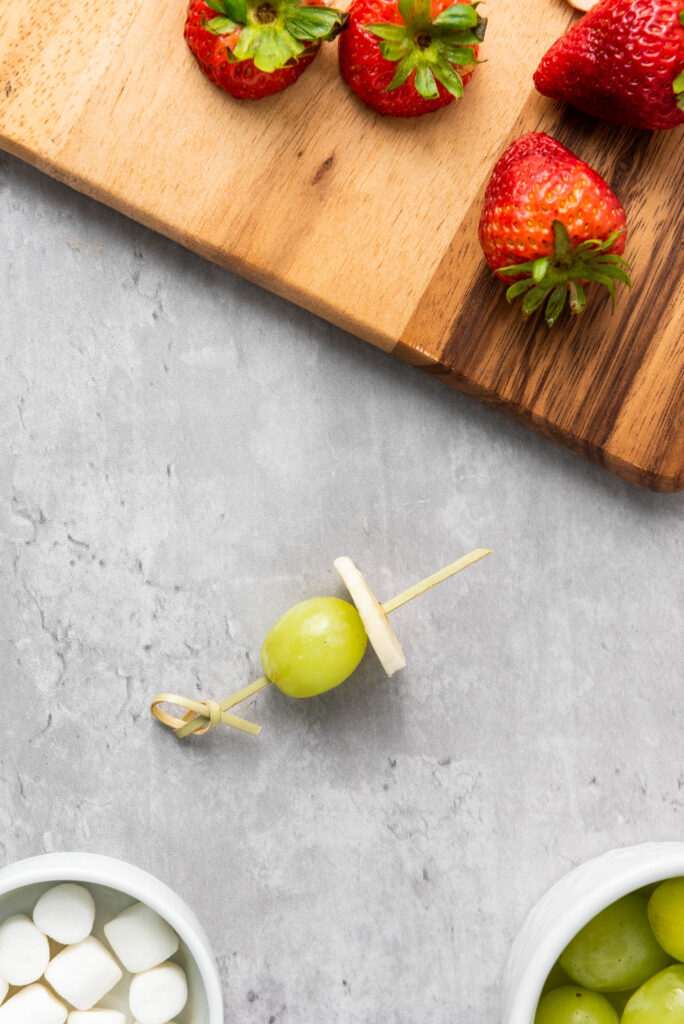 A picture of a grape and banana slice threaded onto a skewer.