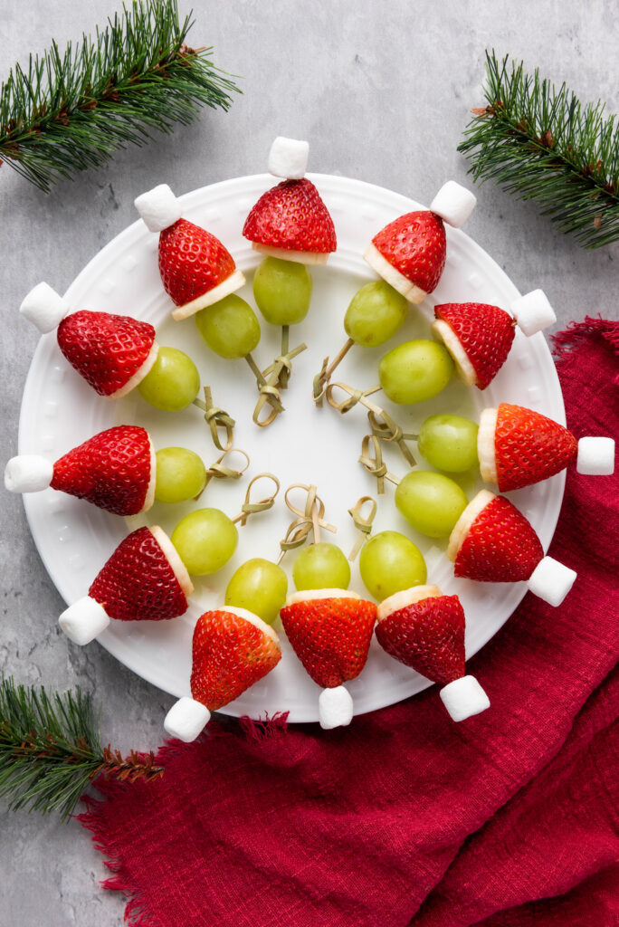 A picture of Christmas themed fruit skewers arranged in a circle on a plate.