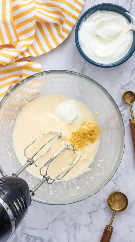 A picture of whisked butter and eggs in a bowl with vanilla extract and lemon zest dumped into the bowl.