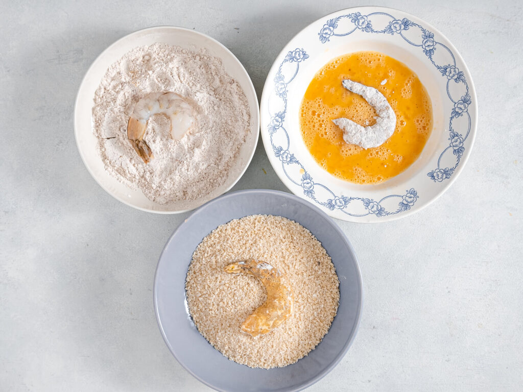 A picture of raw shrimp in process of being breaded.