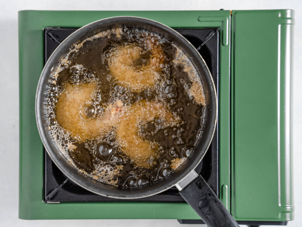 A picture of breaded shrimp frying in a skillet.