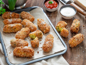 A picture of a platter of mozzarella stuffed potato croquettes with dipping sauces nearby.