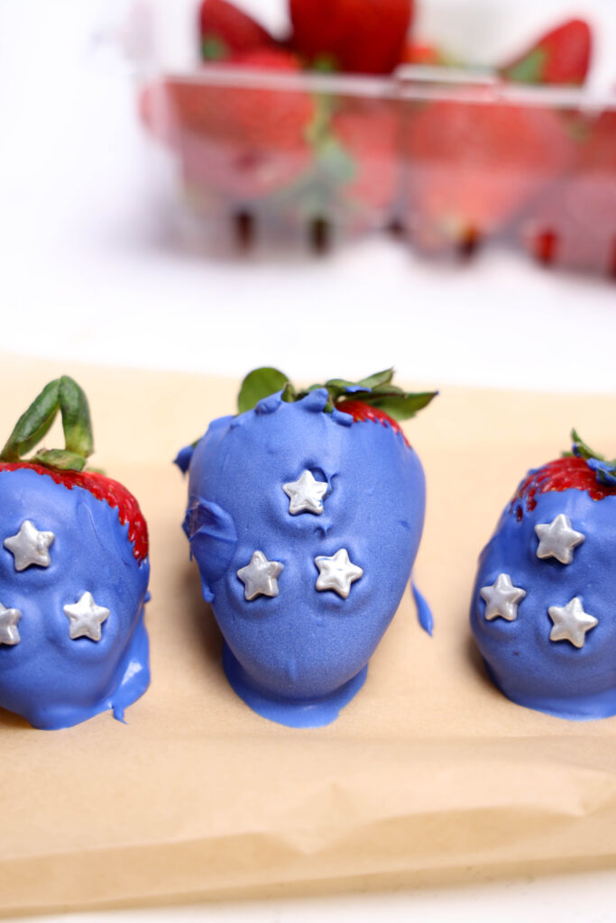 A picture of blue candy coated strawberries inlaid with silver candy stars.
