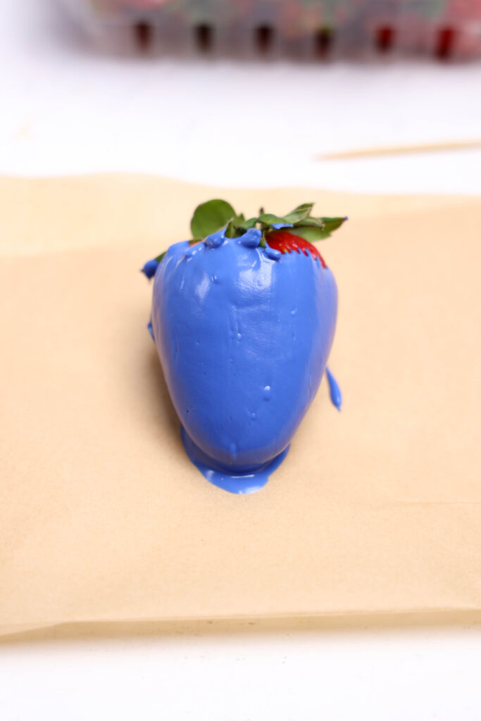 A picture of a single blue candy coated strawberry.