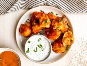 A picture of buffalo cauliflower wings with dipping sauce.