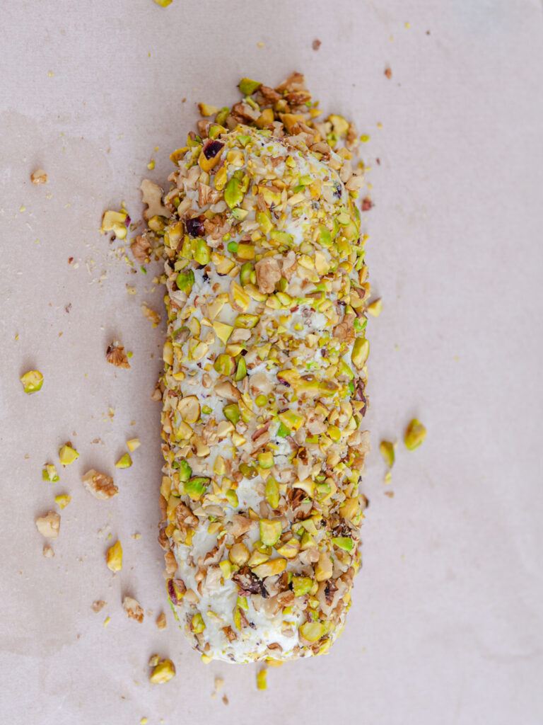 A picture of a cheese log covered with a pistachio nut mixture.