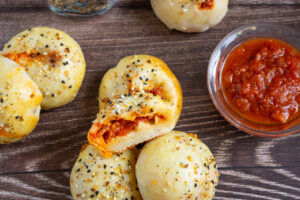 A picture of pepperoni stuffed mini bagels with a bite taken out of one.