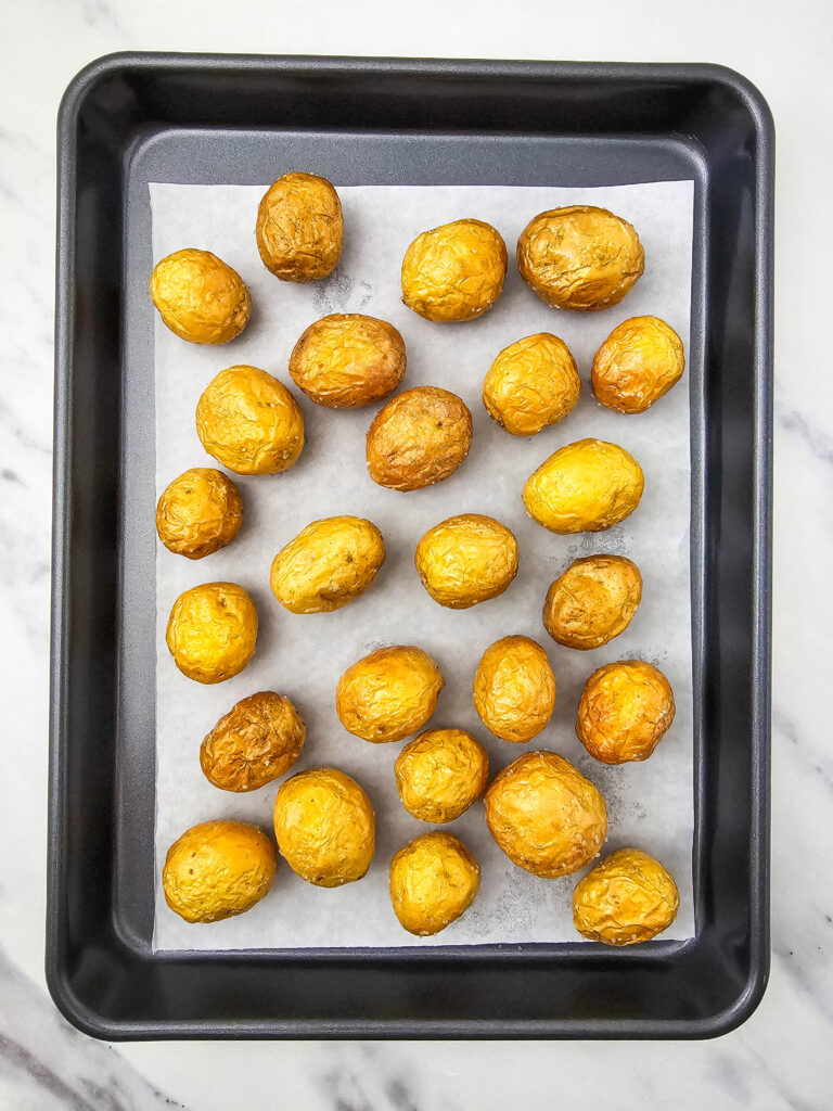 A picture of cooked mini potatoes on a baking pan.