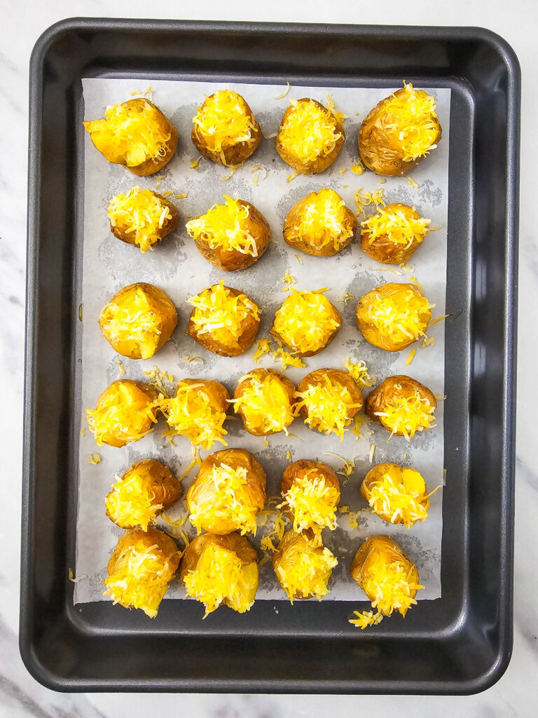 A picture of cooked mini potatoes topped with cheese.