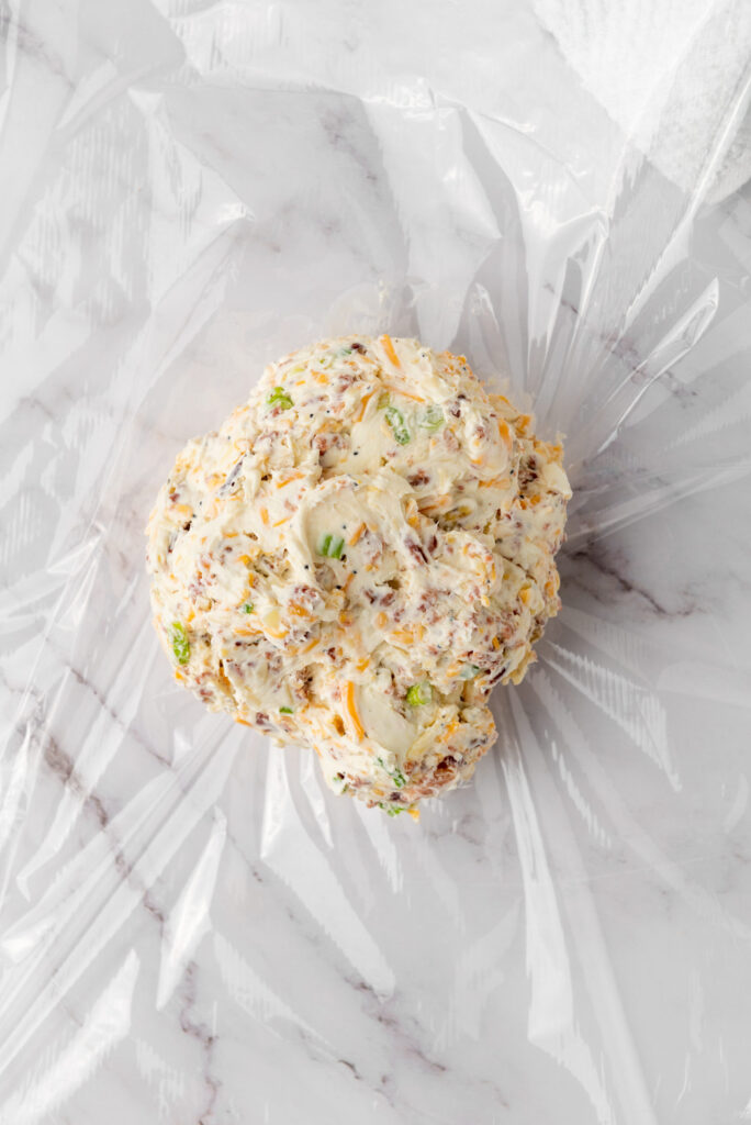 Put a piece of saran wrap on the counter and put the cheese ball in it