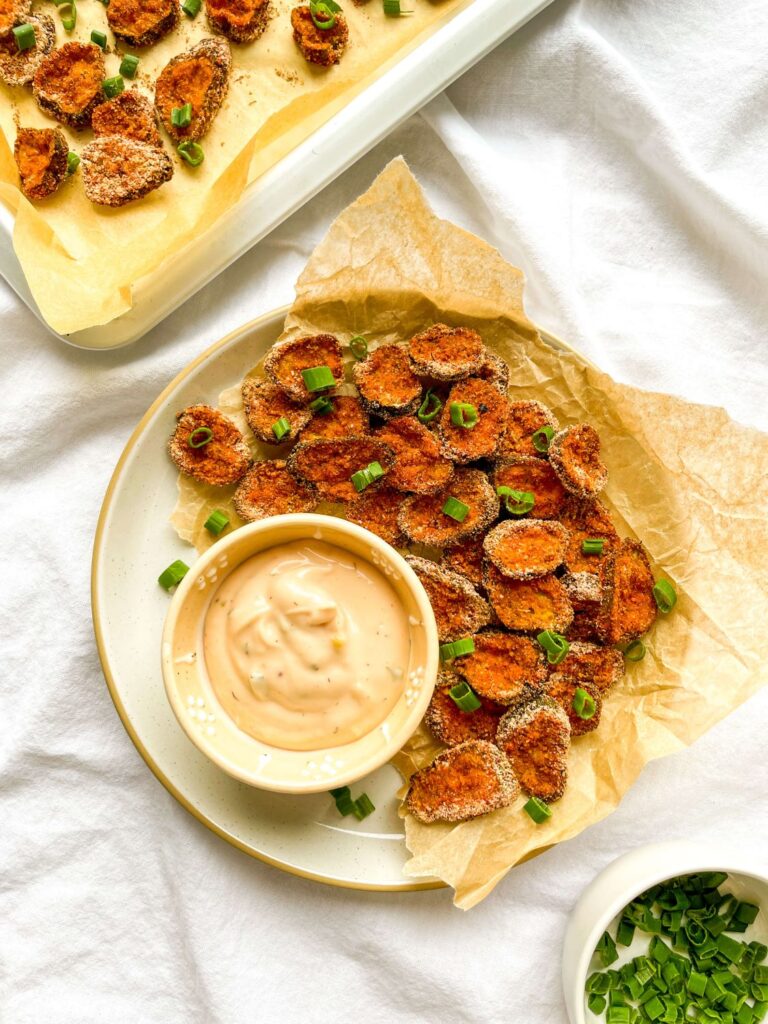 A picture of baked pickle chips on a plate with chipotle ranch dipping sauce